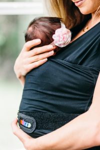 newborn is held in skin-to-skin carrier. 